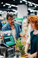 Customer complaining to cashier at supermarket checkout counter