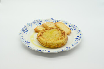 A plate of food with a round yellow pastry and a piece of bread