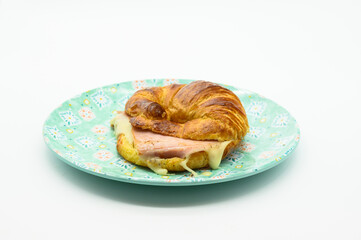 A croissant with ham and cheese on a plate