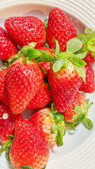 Fresh ripe strawberries on a white plate, ideal for summer fruit, vegan diet concept