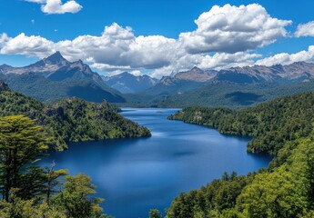Breathtaking Aerial View of Tranquil Lake Surrounded by Majestic Mountains and Lush Green Forests Under a Bright Blue Sky with Fluffy Clouds