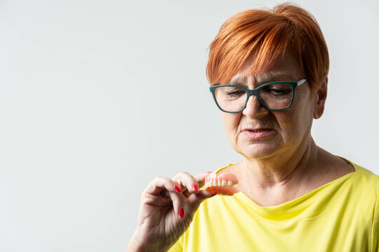 Happy woman over 72 years old be smile with a few broken teeth and holding dentures in hand. Dentures for prosthetic devices constructed to replace missing teeth and helping to chew food.	
