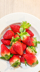 Fresh strawberries in a white bowl, perfect for summer desserts and healthy eating concepts