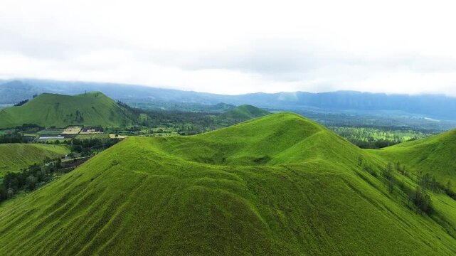 aerial view of green hills peak with grassland and mountain views of Wurung Crater, Indonesia. Aerial shot of the green grassy peak of the mountain crater.