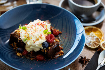 Brownie cake with salted caramel. Anglaise foam, raspberry sauce, praline nut and fresh berry. Delicious sweet dessert food closeup served for lunch in modern gourmet cuisine restaurant