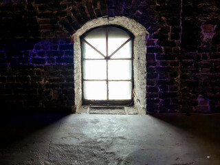 Obraz premium Old stone wall with a vintage window casting a soft light. The contrast between dark textures and illuminated glass creates a moody atmosphere.