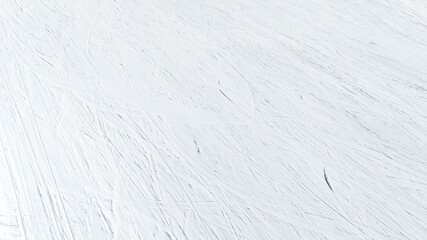 Aerial view of a ski slope with lots of snow. White background ideal for texture and pattern. There are the stripes and grooves left by the skis on the snow.