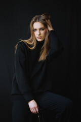 Fashion editorial portrait of a young woman in a black oversized sweater. Her confident expression...