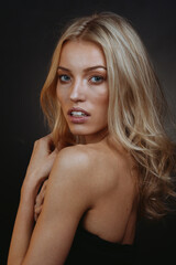 Naklejka premium Serene Blonde Vision: Blue-Green Eyes and Flowing Hair on Dark Canvas