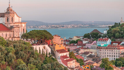 Fototapeta premium Tourists at the viewpoint Miradouro da Graca look at Lisbon overview aerial timelapse. Portugal