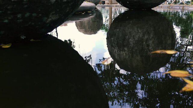 Large stone balls are reflected in the water surface of the fountain