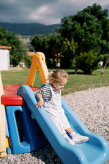 Little girl slides down a slide on a playground