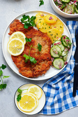 Traditional Viennese schnitzel on a plate with cucumber and potato salad.selective focus