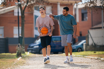 Two happy friends walking and talking after playing basketball outdoors