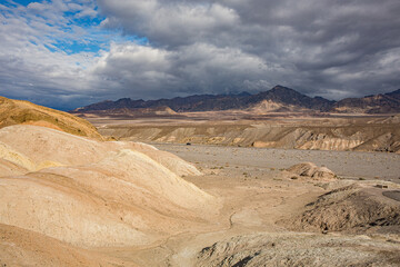 Barren Desert Hills with Dramatic Sky and Mountain Range in the Distance