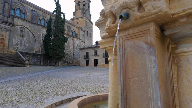 Very old water fountain in front of the medieval stone church of Baeza, Jaen, Andalusia.