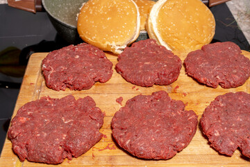 Fresh, raw hamburger patties on a wooden cutting board, ready for cooking. The texture and arrangement highlight the simplicity of burger preparation.