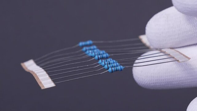 Close-up of a THT 1/4W resistor with a color-coded band pattern, positioned on a dark background. A classic electronic component used in Through-Hole Technology (THT) assembly. Ideal for applications