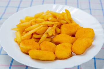 French fries and golden chicken nuggets on a plate close-up