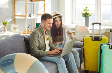 Happy tourist couple, young family online choosing trip, booking tickets flight from home, plan travelling, dreaming of bright summer trip holiday beach fun, packing luggage bag for vacation travel