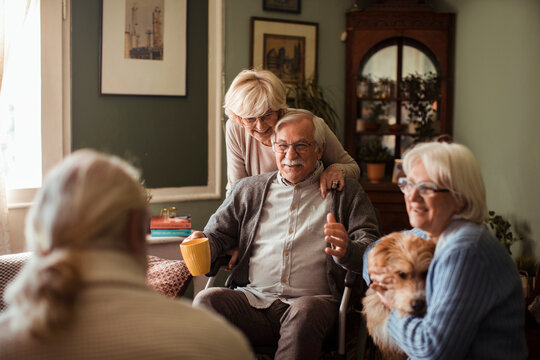 Happy senior friends spending time together with dog at home