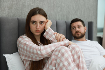 Man comforting his resentful girlfriend on bed at home, selective focus