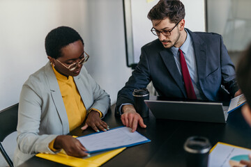 Group of businesspeople in formal attire discussing financial reports