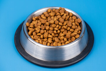 Dry dietary food for cats and dogs in a bowl isolated on solid color background. Healthy pet nutrition and feeding routines.