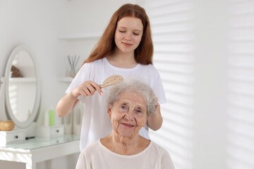 Granddaughter brushing her grandmother with brush at home