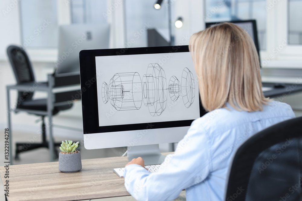 Poster technician making digital engineering drawing on computer at desk in office, back view