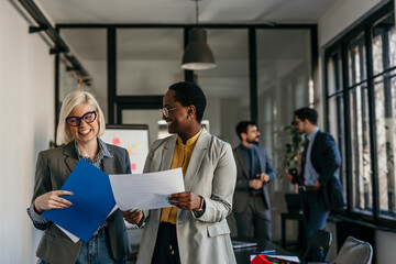 Professional coworkers standing and working on paperwork at a bright office