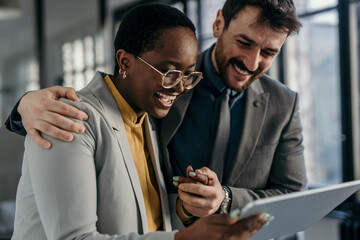 Two business professionals standing in a modern office, collaborating on a tablet