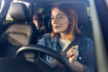 Woman fastening seat belt in car with child in backseat