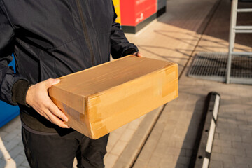 Man Standing with a Parcel Box in Front of Self-Service Lockers – Waiting to Pick Up or Drop Off...