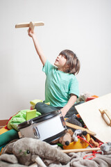 A young boy is playing with a wooden toy airplane.