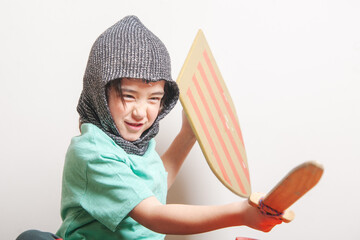 A young child is wearing a knight's costume and holding a wooden shield and sword