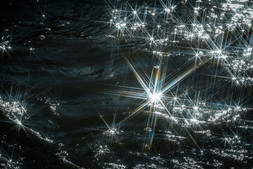 Sunlight reflects off flowing water, creating a dazzling starburst effect. The contrast between...
