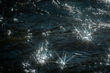 Sunlight reflects off flowing water, creating a dazzling starburst effect. The contrast between...