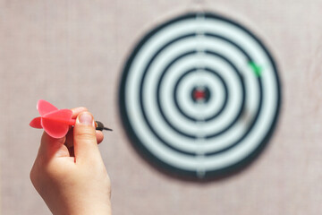 Playing darts, child's hand aiming a dart at a target