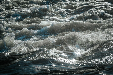 Sunlight reflects off the rippling water, creating a mesmerizing starburst effect. The bright,...
