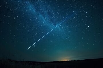 Shooting star in the night sky over a field. Majestic shooting star trail for astronomical events and night sky backgrounds. Magical space scene for astrology.