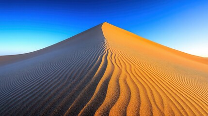 Golden sand dune peak under clear blue sky, texture lines, warm sunlight