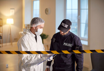 Forensic expert and police officer conduct investigation in victims apartment analyzing...