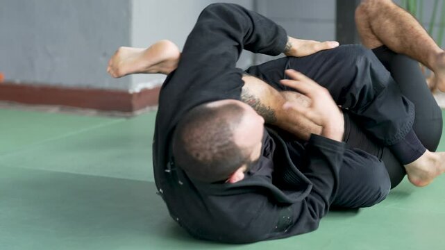 Two jiu-jitsu athletes practice a triangle choke hold during training