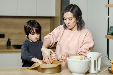 Mother and son are preparing a cherry cake together