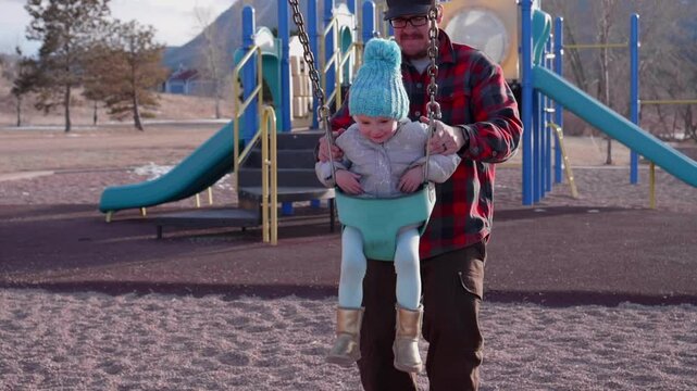 Father Pushing Daughter on the Swingset