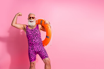 Photo of positive aged man swimmer lifeguard hold buoy raise fists up winning wear swimsuit isolated pink color background