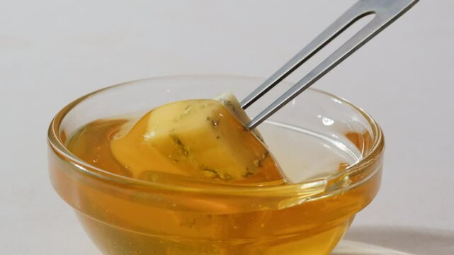 Tasty blue cheese with rosemary, honey and walnuts on white table, close up of Dorblu in cafe pouring in honey.