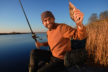 Fisherman with rod and caught fish at riverside