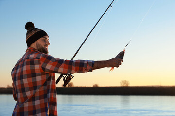 Fisherman with rod and caught fish at riverside